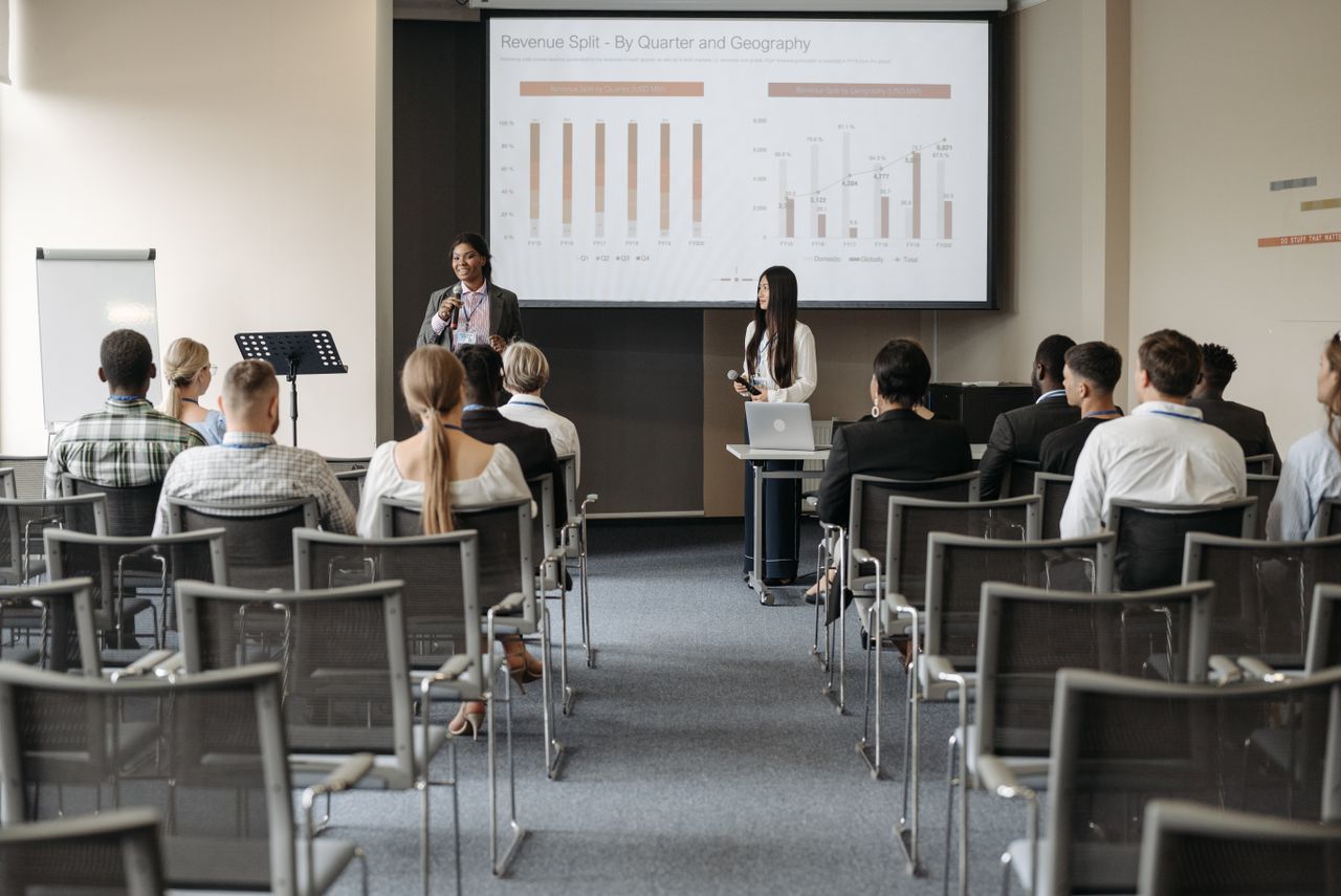 Professional business seminar with audience listening to presenters sharing data insights.
